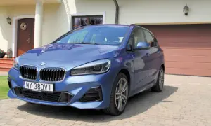 Niebieski minivan BMW serii 2 Active Tourer zaparkowany przed domem.